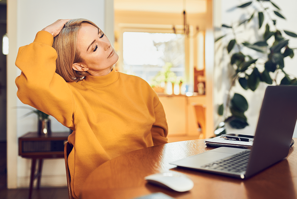 cs-pleaz-internal-2 a woman in a yellow sweater takes a break by stretching at her desk